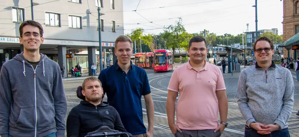Fünf Mitglieder des Landesvorstands stehen nebeneinander auf einem Bahnhofsvorplatz in Mainz, im Hintergrund fährt eine rote Straßenbahn.